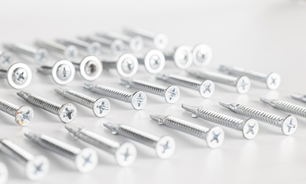 Tapping screws made of steel on Gray background, metal screw, iron screw, chrome screw, screws as a background, wood screw, concept industry. copy space for text.